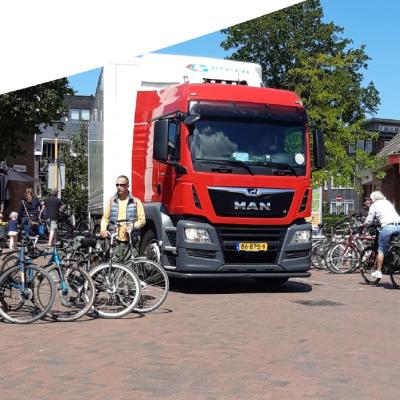 Vrachtwagen en fietsers midden in het dorp